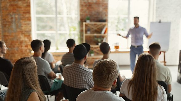 © master1305 -istock.com Ein Mann steht vor einem Flipchart und hält einen Vortrag vor einer Gruppe