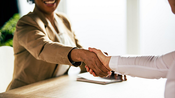 © fotstorm - istock.com Zwei Frauen unterscheidlicher Ethnien schütteln sich die Hände