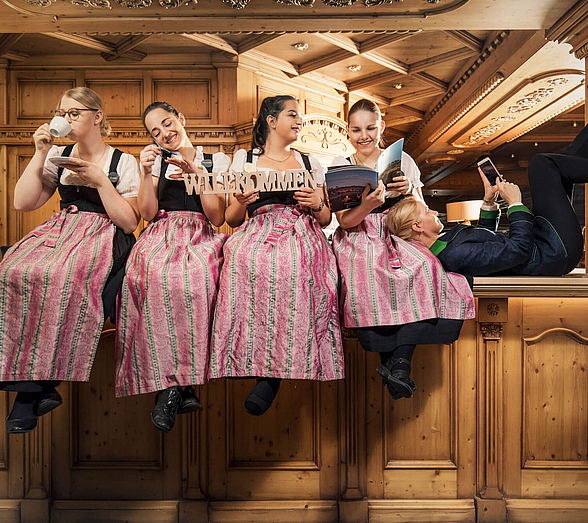 Frauen im Drindl sitzen an einer Hotelrezeption