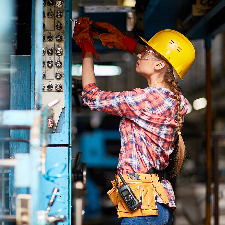 Junge Frau mit Helm kontrolliert Elektronik