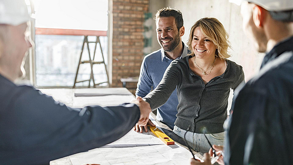 © skynesher – istock.com  Frau und Mann begrüßen einen Handwerker auf der Baustelle