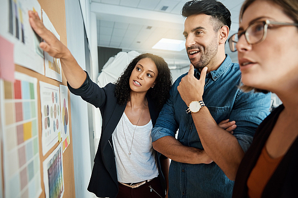 Ein Team arbeitet gemeinsam an einer Pinnwand und ermittelt den Weiterbildungsbedarf im Unternehmen.