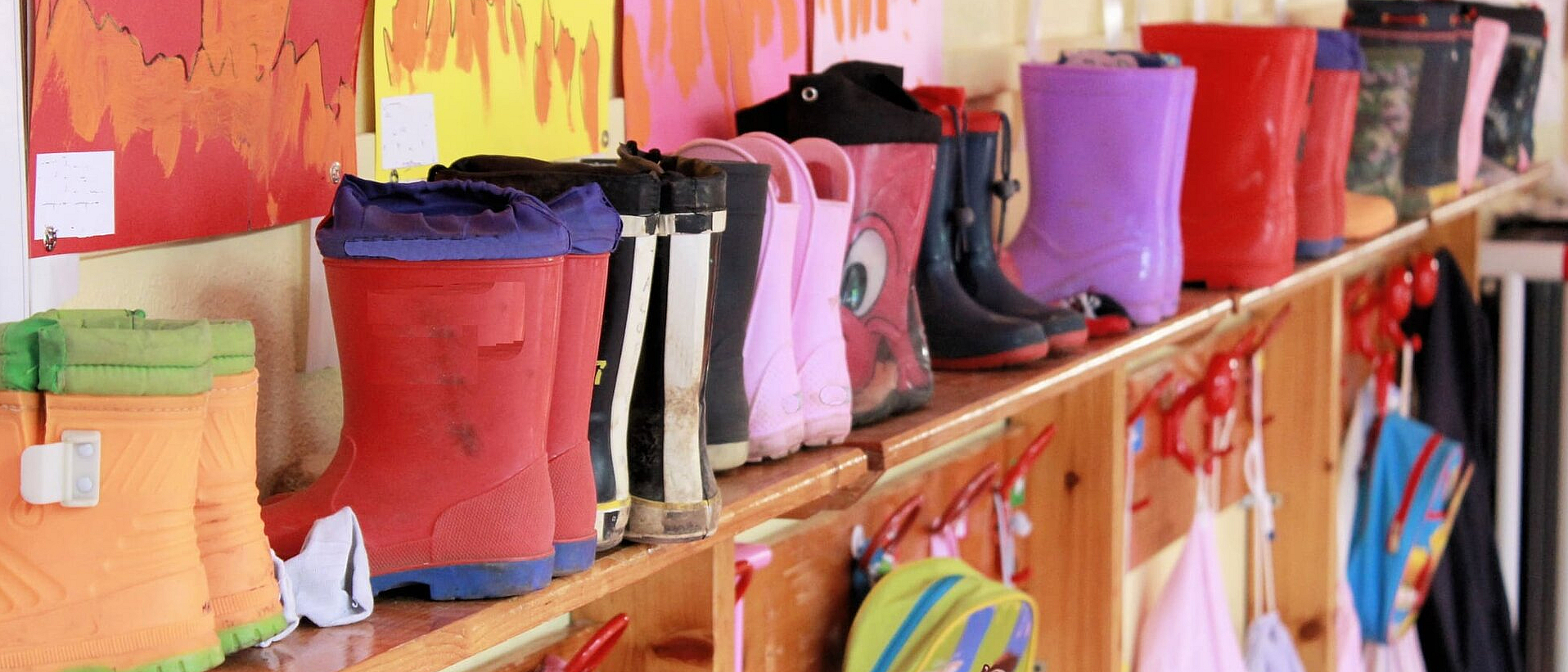 © marcobir - istock.com Kindergummistiefel aufgereiht in einem Kindergarten
